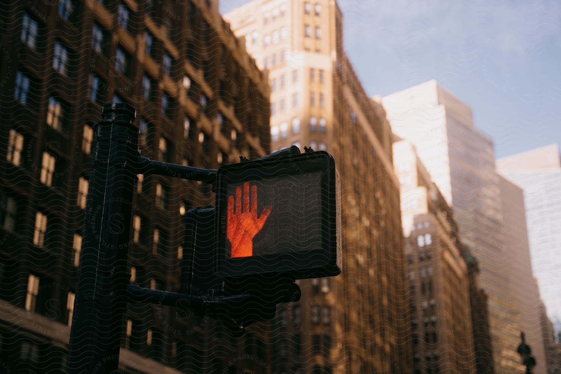 A Pedestrian Signal Displays The Hand Symbol In Front Of Several Buildings Of Different Heights