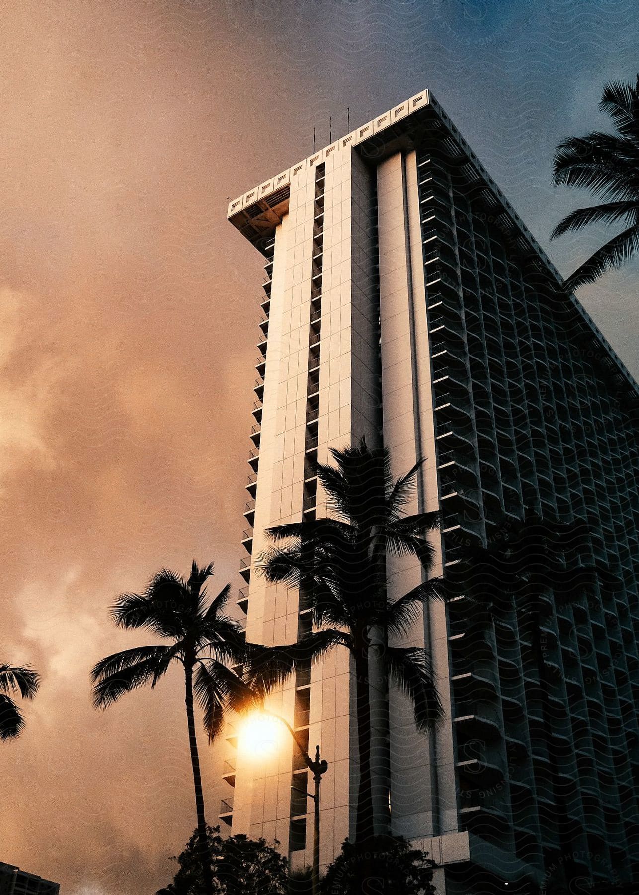 A daytime view of a city with a high rise building palm tree and hotel