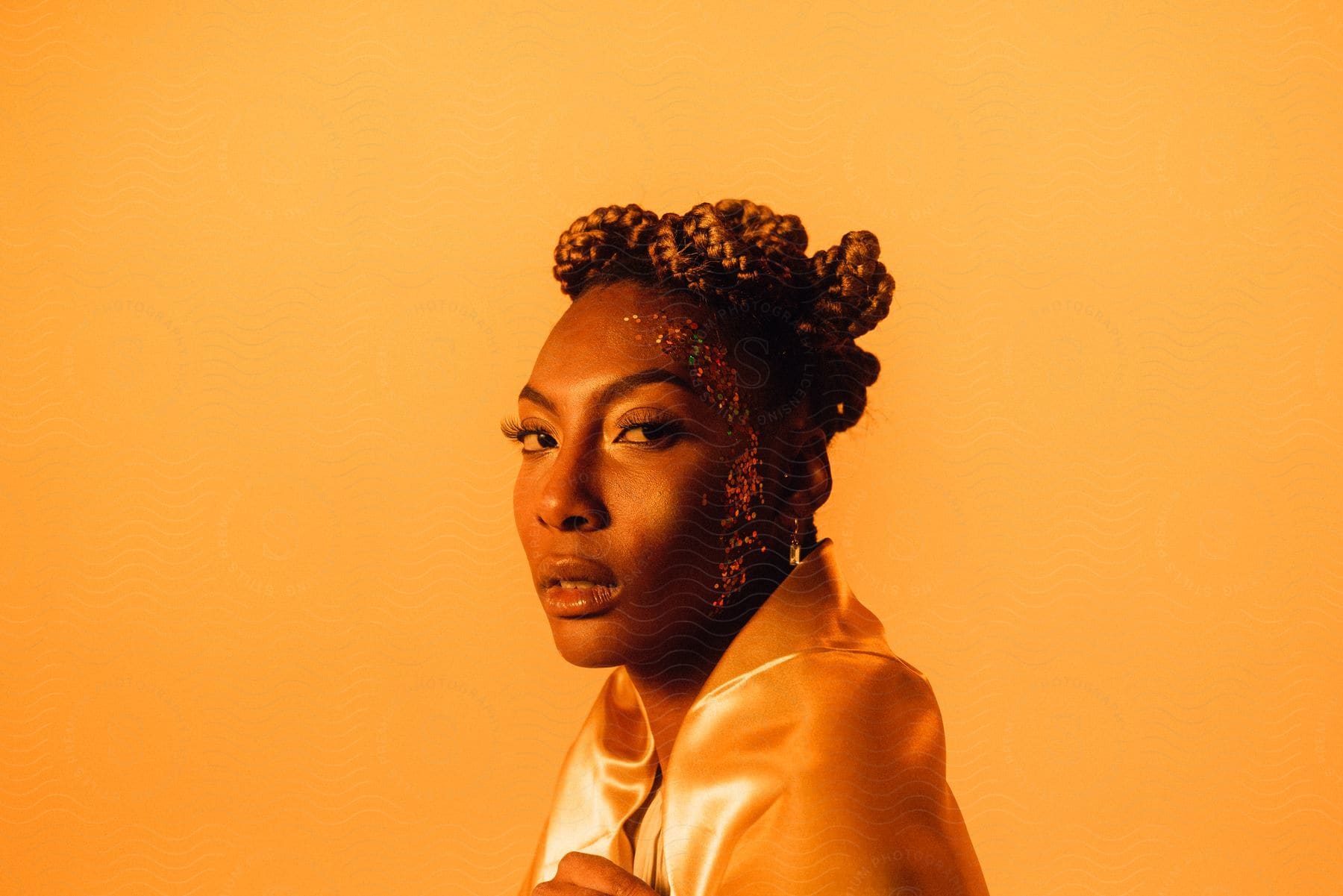 Woman with yellow silk top brown braided hair faces camera with eye contact