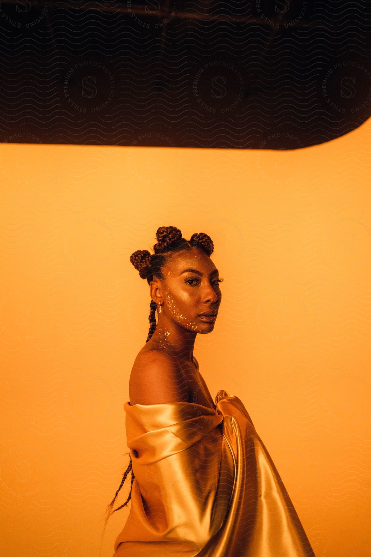 A woman poses in a dress in orange light