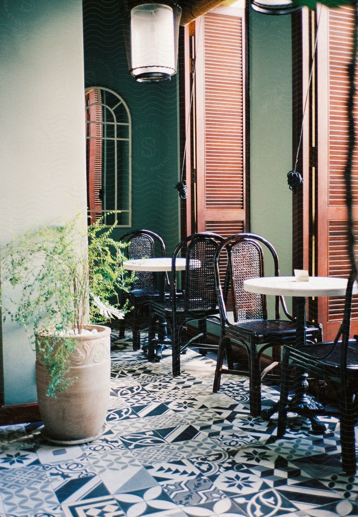 Restaurant interior with white tables black chairs potted plant mosaic floor and open shutter windows