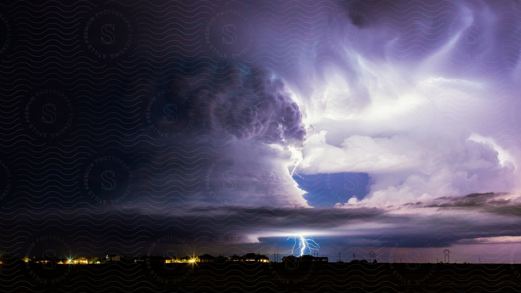 Lightning Bolt Illuminating The Sky Among Large Thick Clouds Near A Town During A Storm