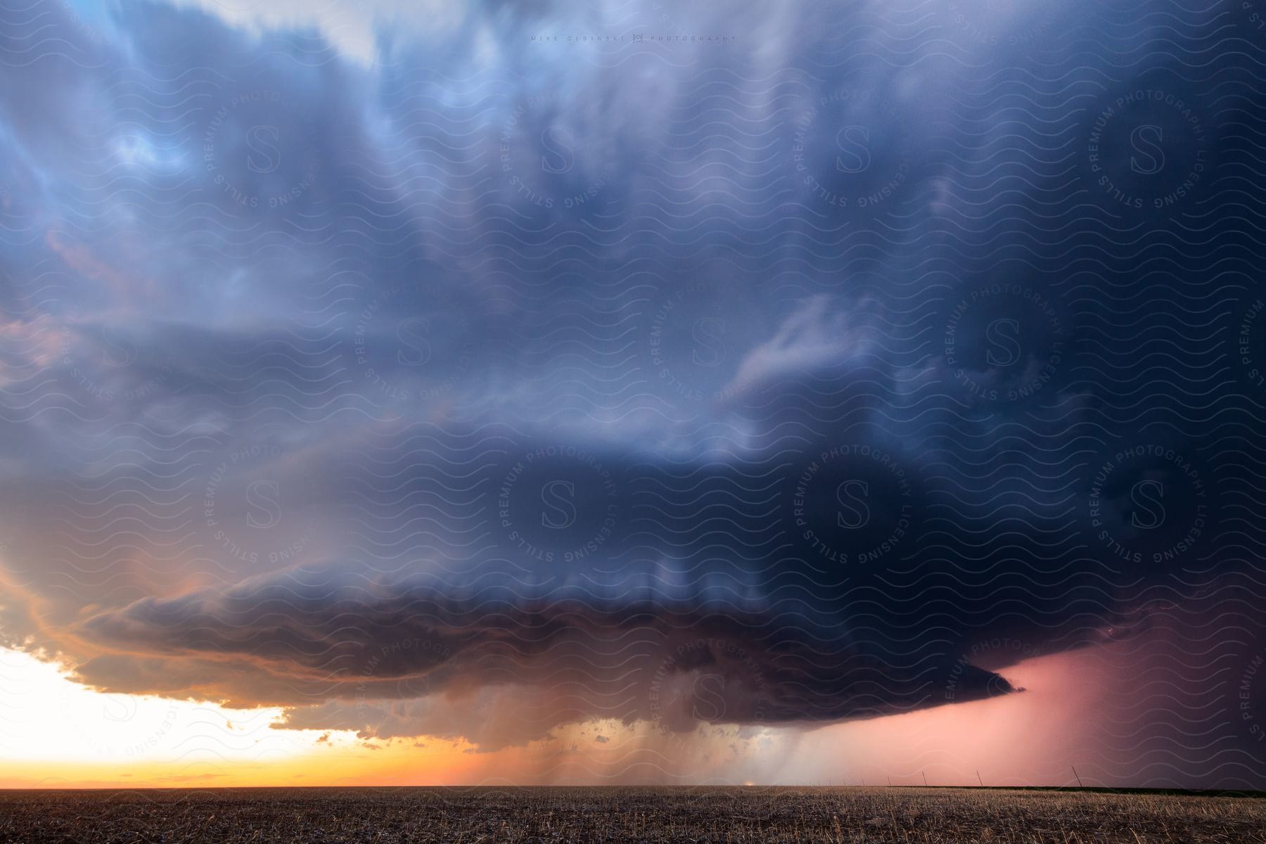 A big cloud storm with lights reflecting in the background at sunset in winona kansas