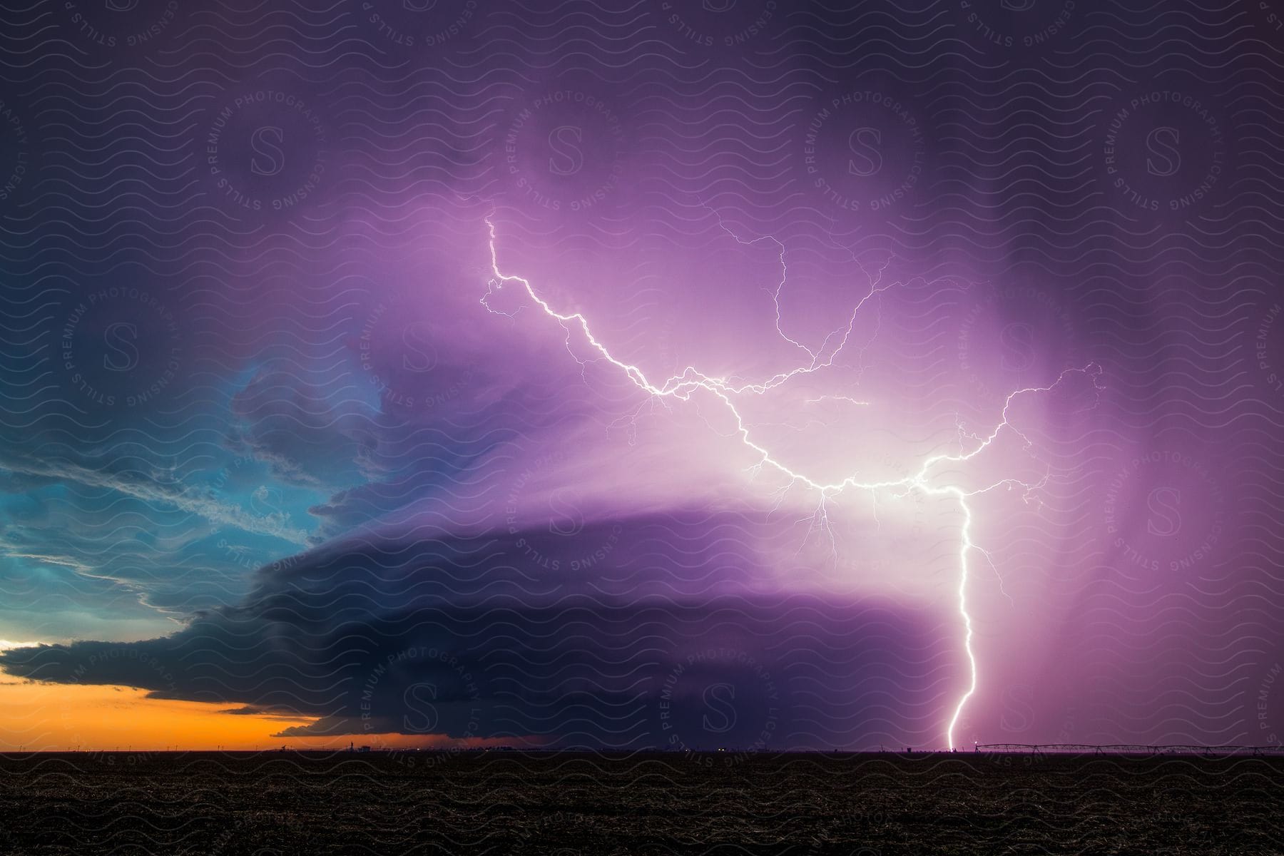 Lightning and rain falling from storm clouds over the mountains in the plains