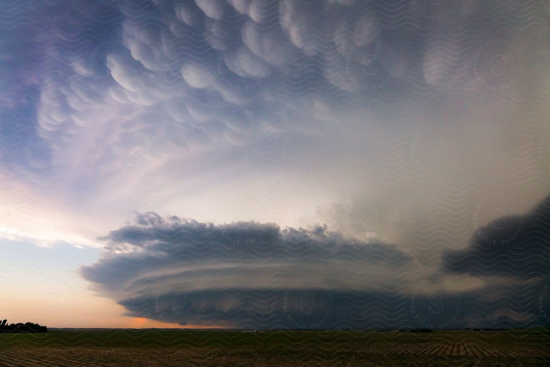 A supercell storm hangs over rural farmland as dark storm clouds move across the sky in arnold nebraska