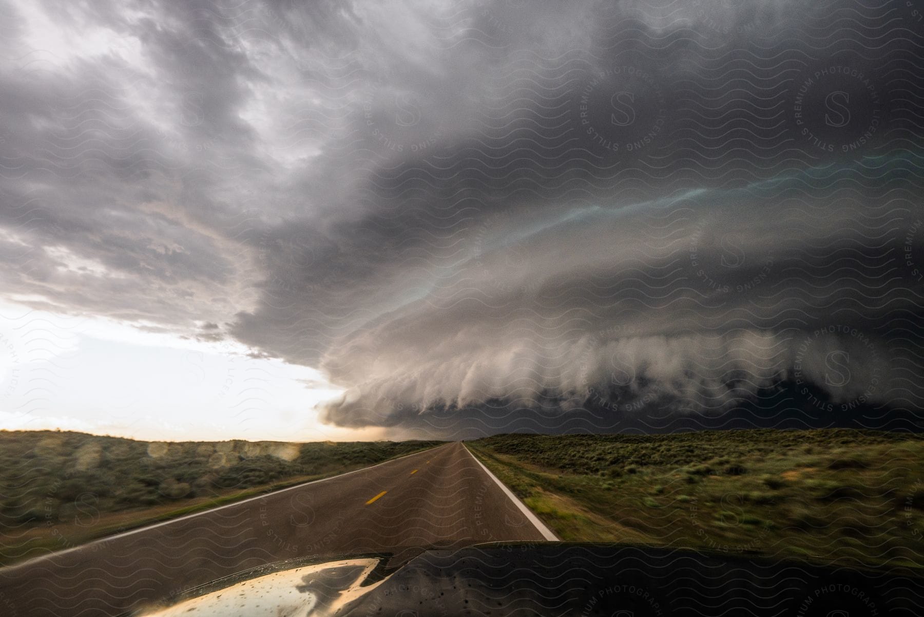 Large storm cloud rolling over the countryside seen from a moving vehicle at evening