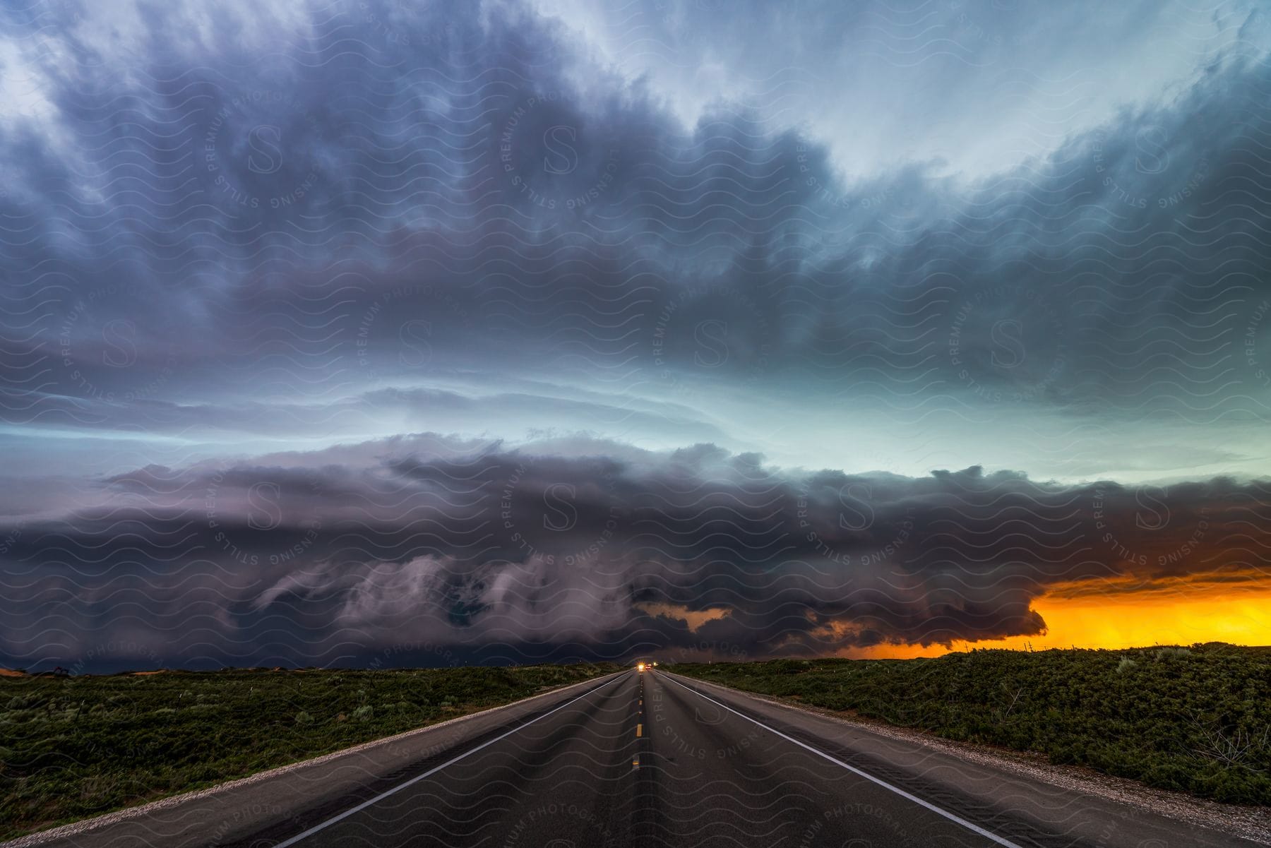 Highway in natural vegetation with dark clouds and duskdawn in the background