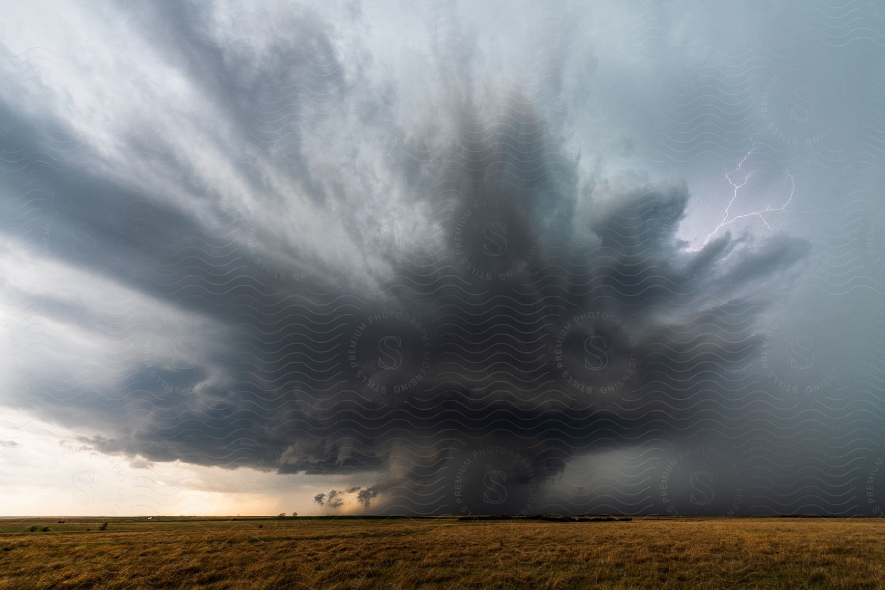 A supercell storm cloud pours down rain as it moves across rural farmland in hoisington kansas