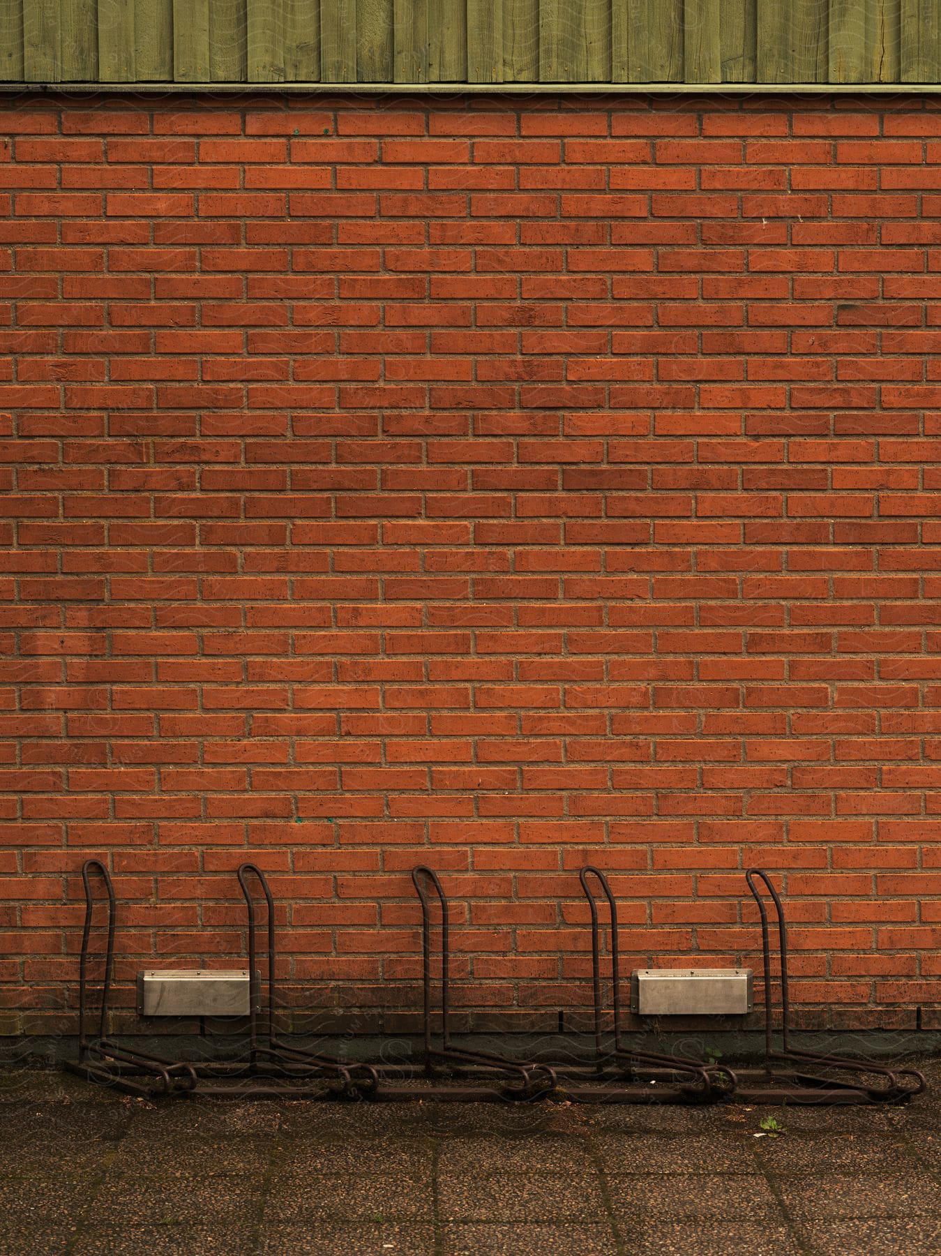 A bicycle rack positioned at the base of a brick wall
