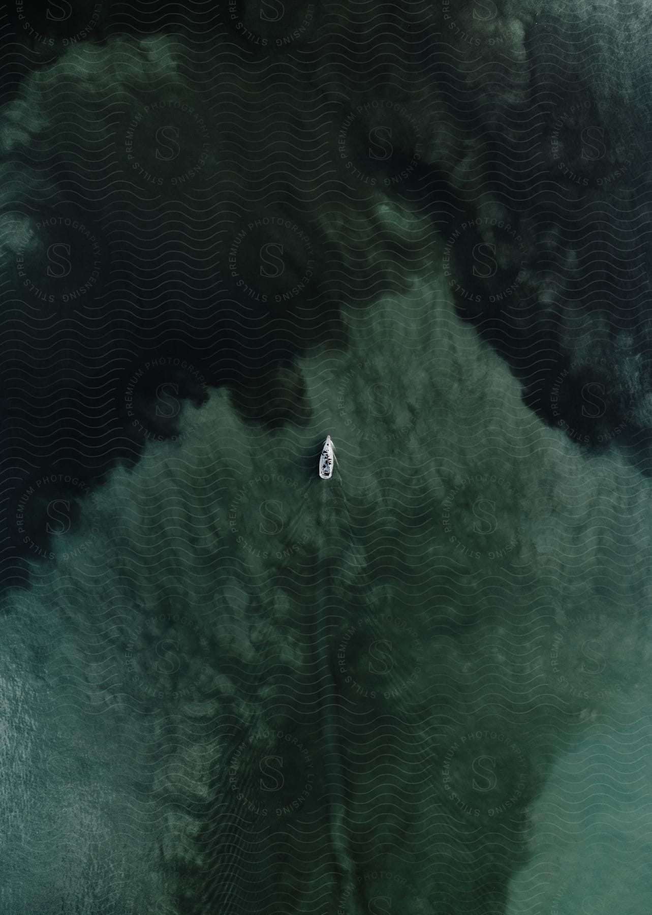 A boat driving on a body of water from an overhead perspective