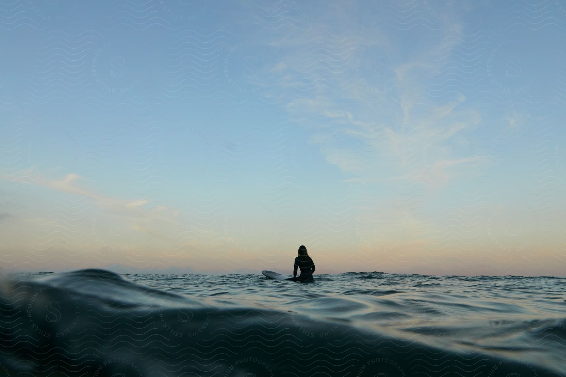 A female surfs on ocean water at dusk