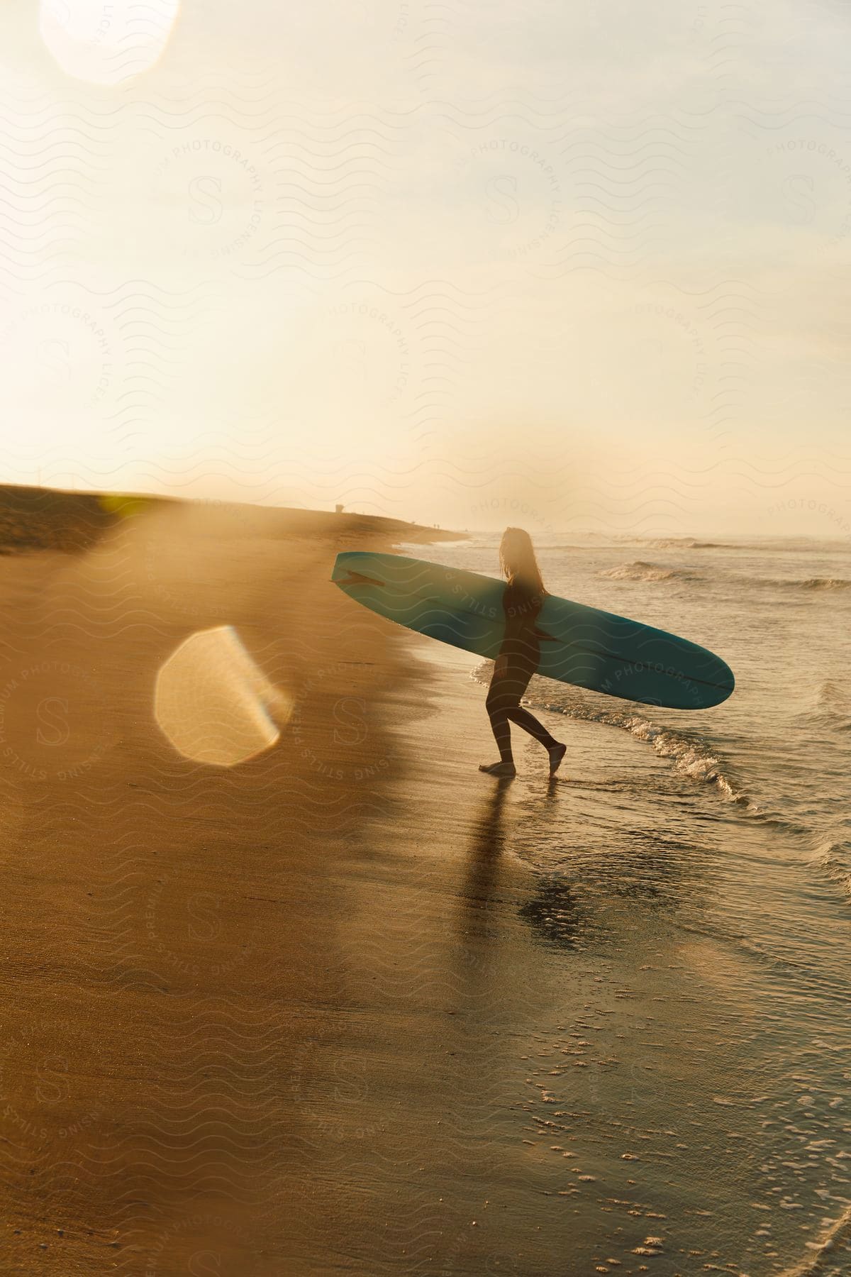 Stock photo of a woman enjoying surfing on the beach surrounded by nature and the ocean