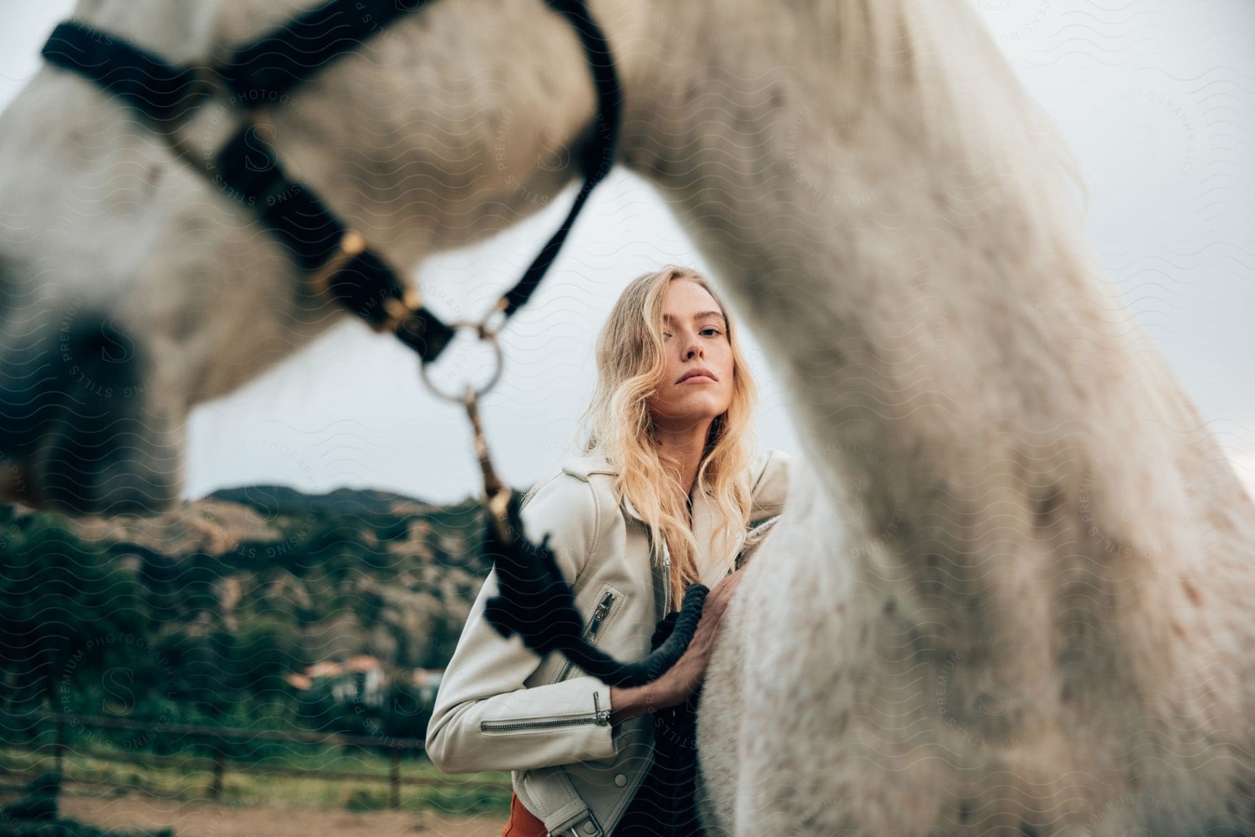 A woman with blonde hair takes a selfie with a horse in nature