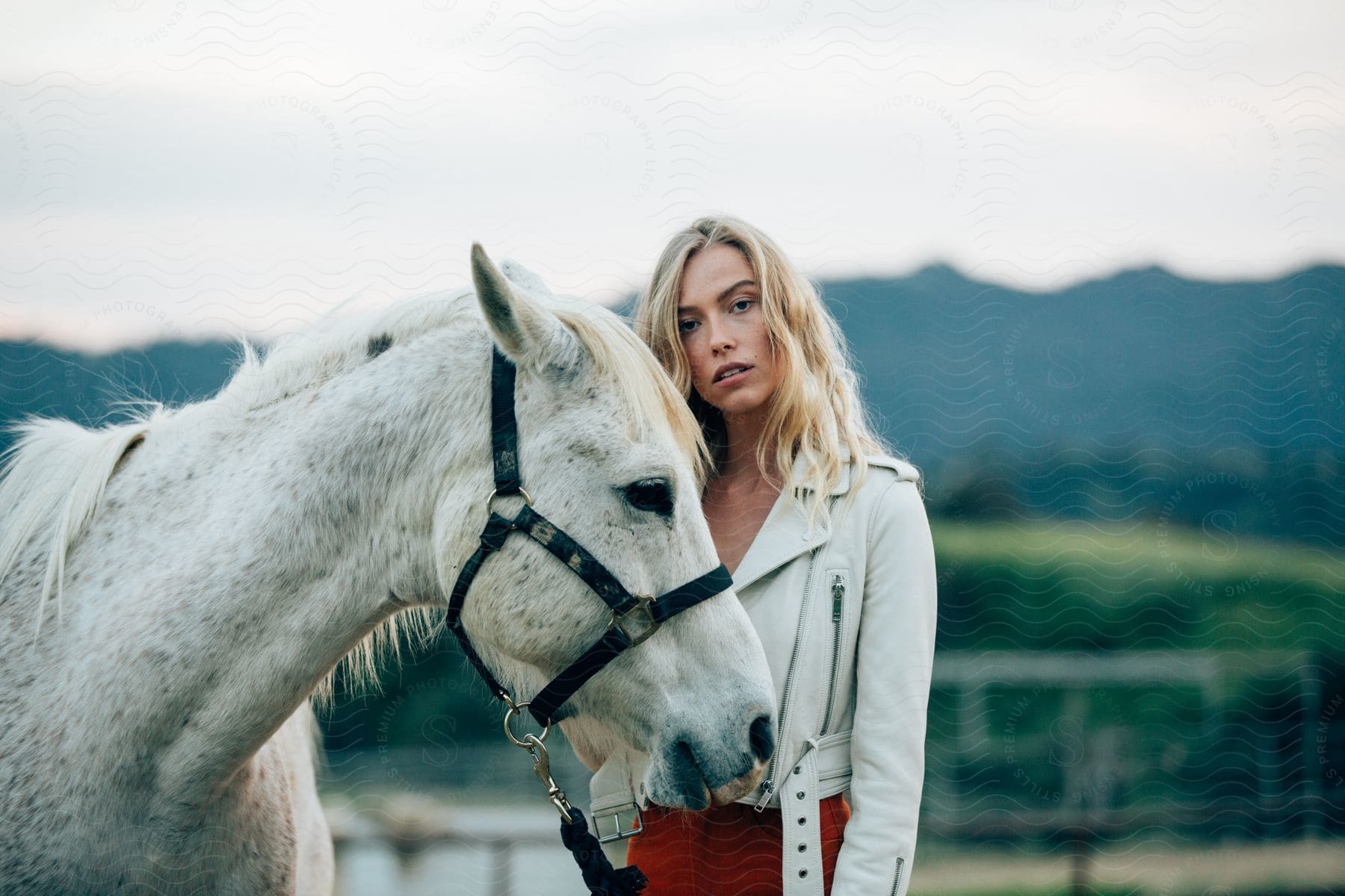 A woman with blonde hair standing next to a horse in the outdoors