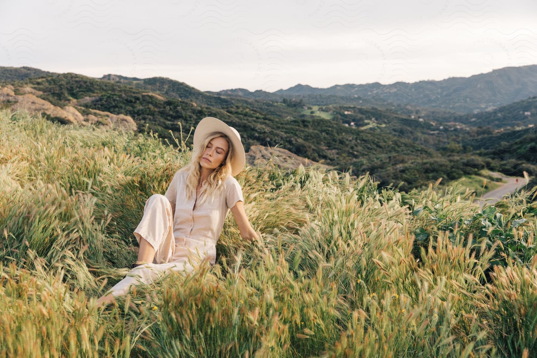 A woman sits in a field wearing a summer outfit