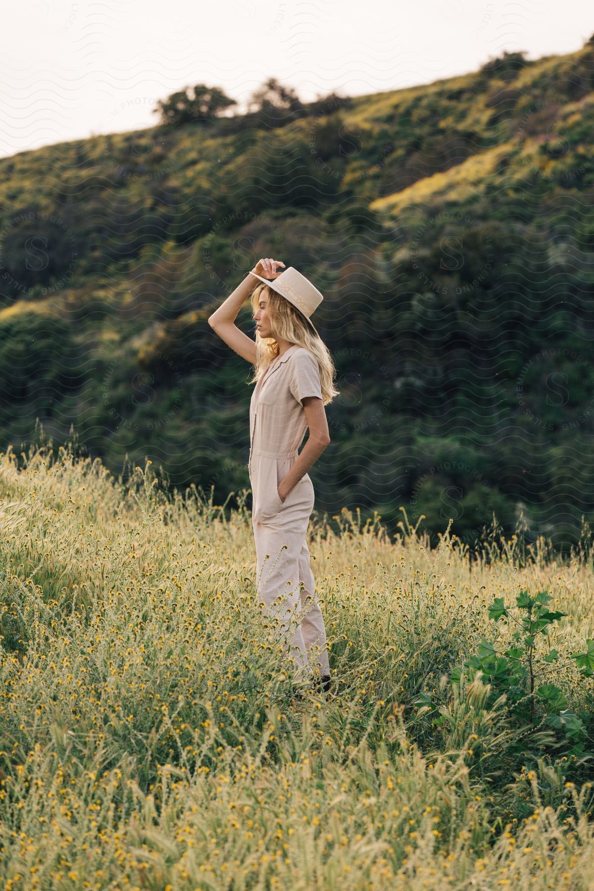 A person standing in a field with a hat and pants under a sunny sky determined