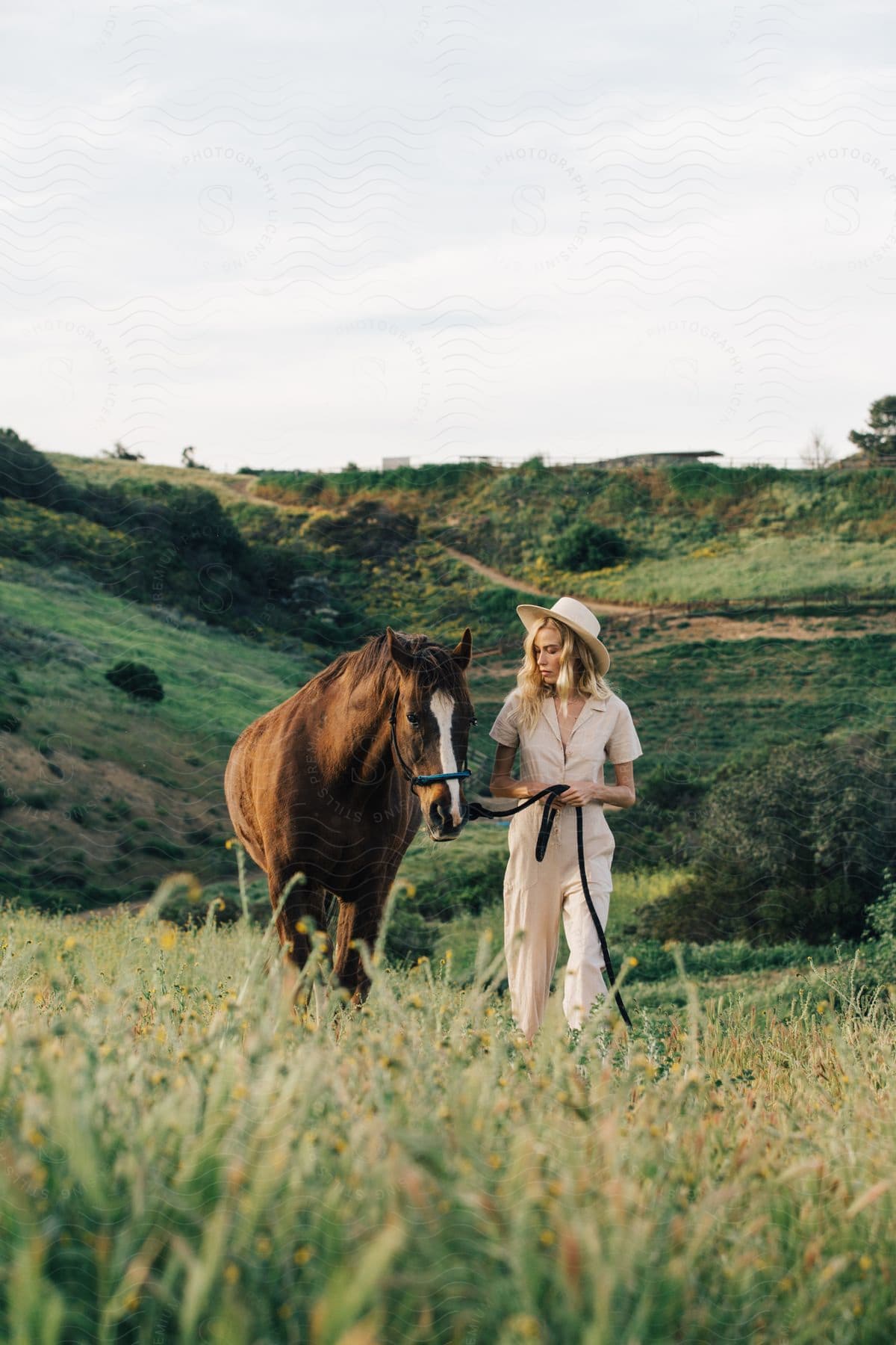 A woman leading a horse through the countryside