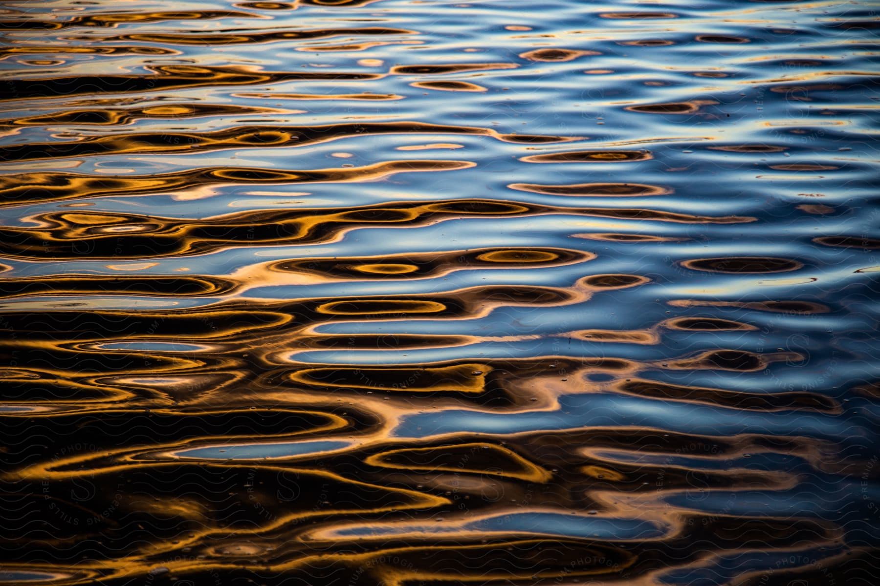 A calm lake with ripples and a car in the background