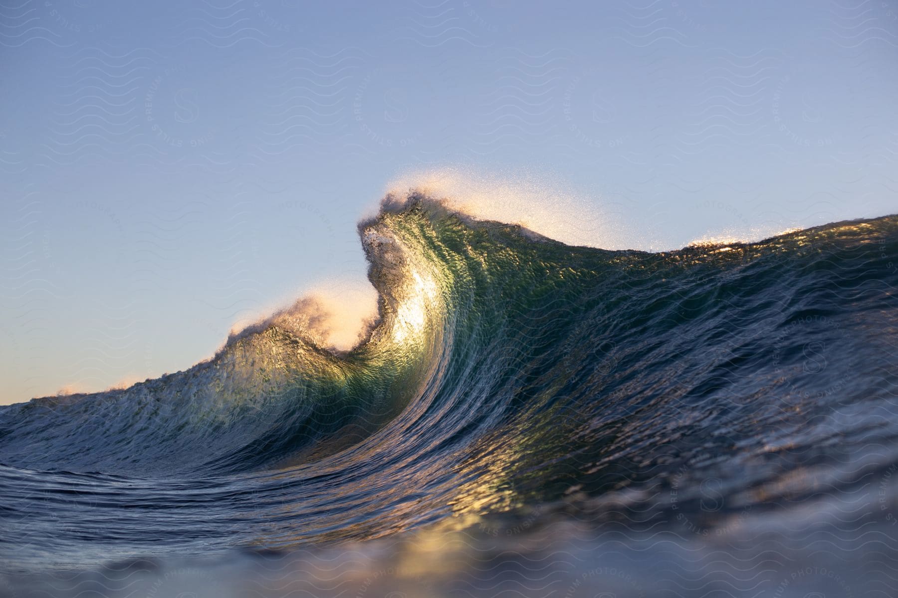 Sun shining through ocean wave breaking against the shore