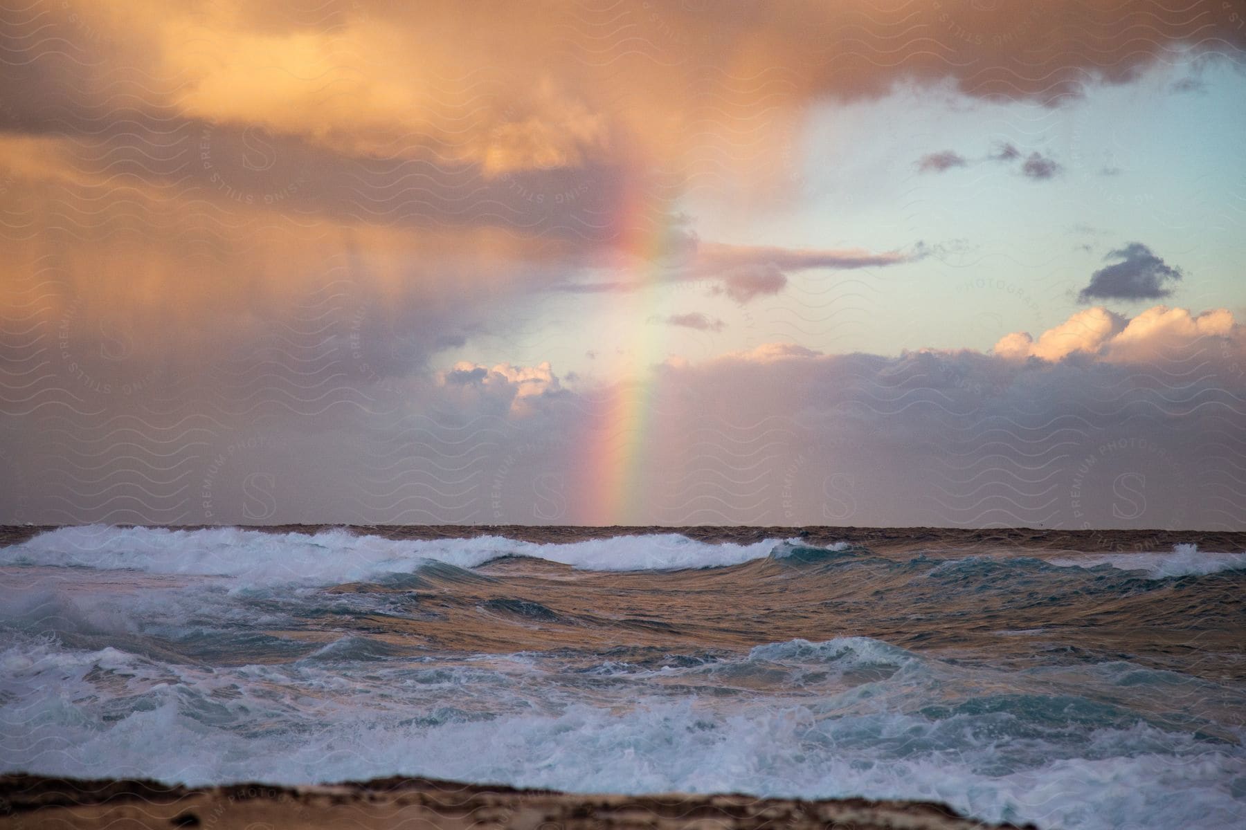 A serene ocean with a rainbow in the sky