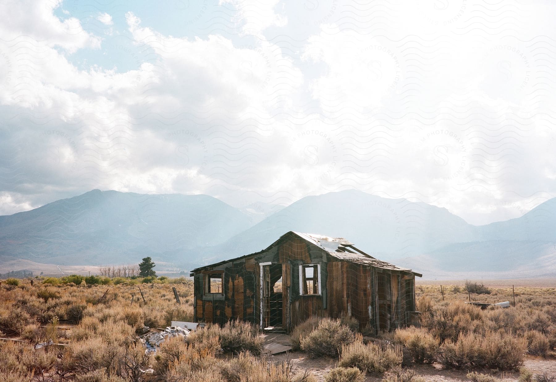 Abandoned hut surrounded by faded grasses and majestic mountains in california