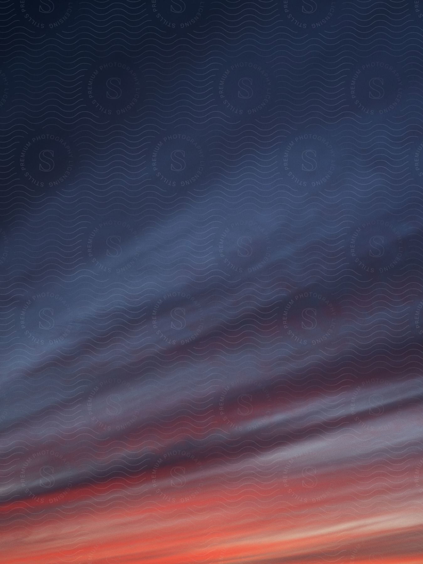 Red and dark blue hues blend together to form a captivating wavelike pattern in the sky at dusk