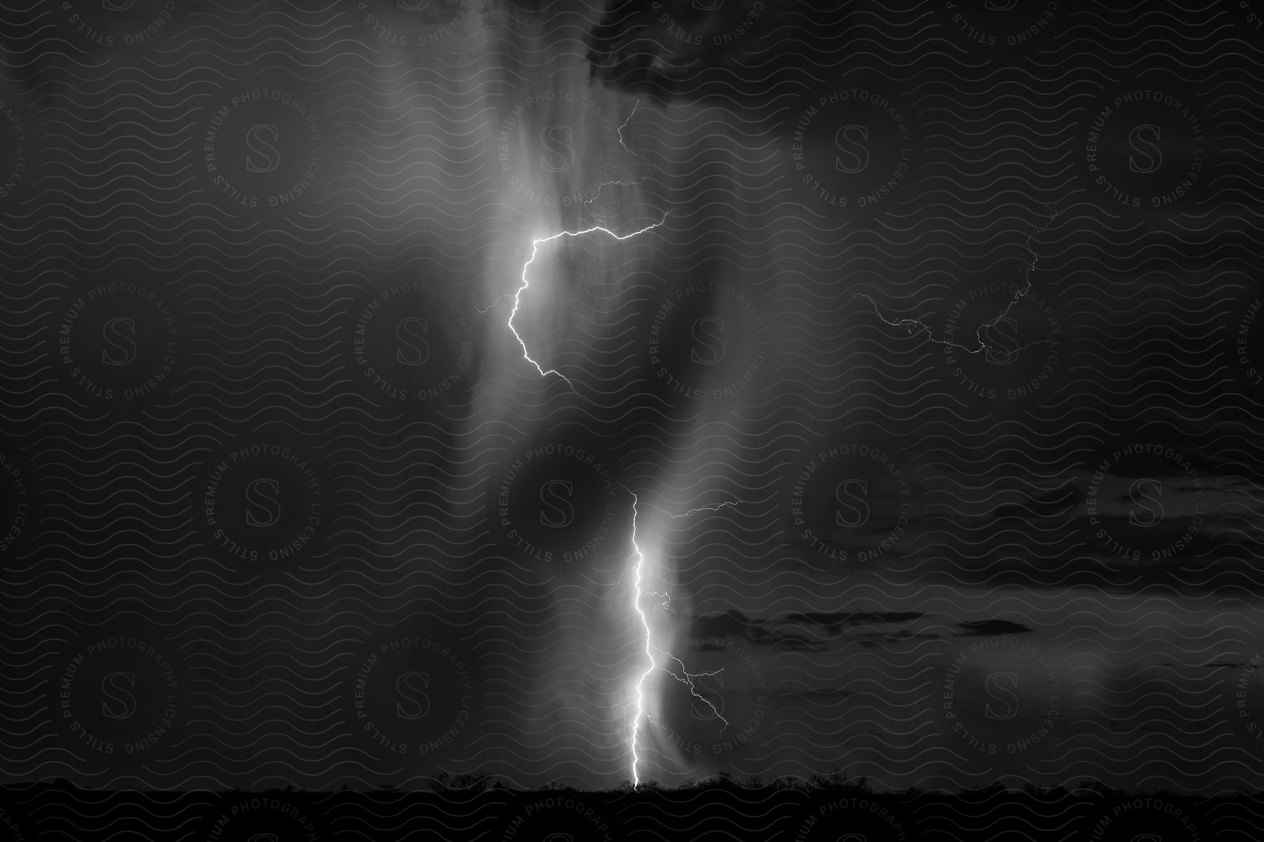 Black and white photo of a thunderstorm with a heavy band of rain partially obscuring a lightning bolt in tonopah arizona