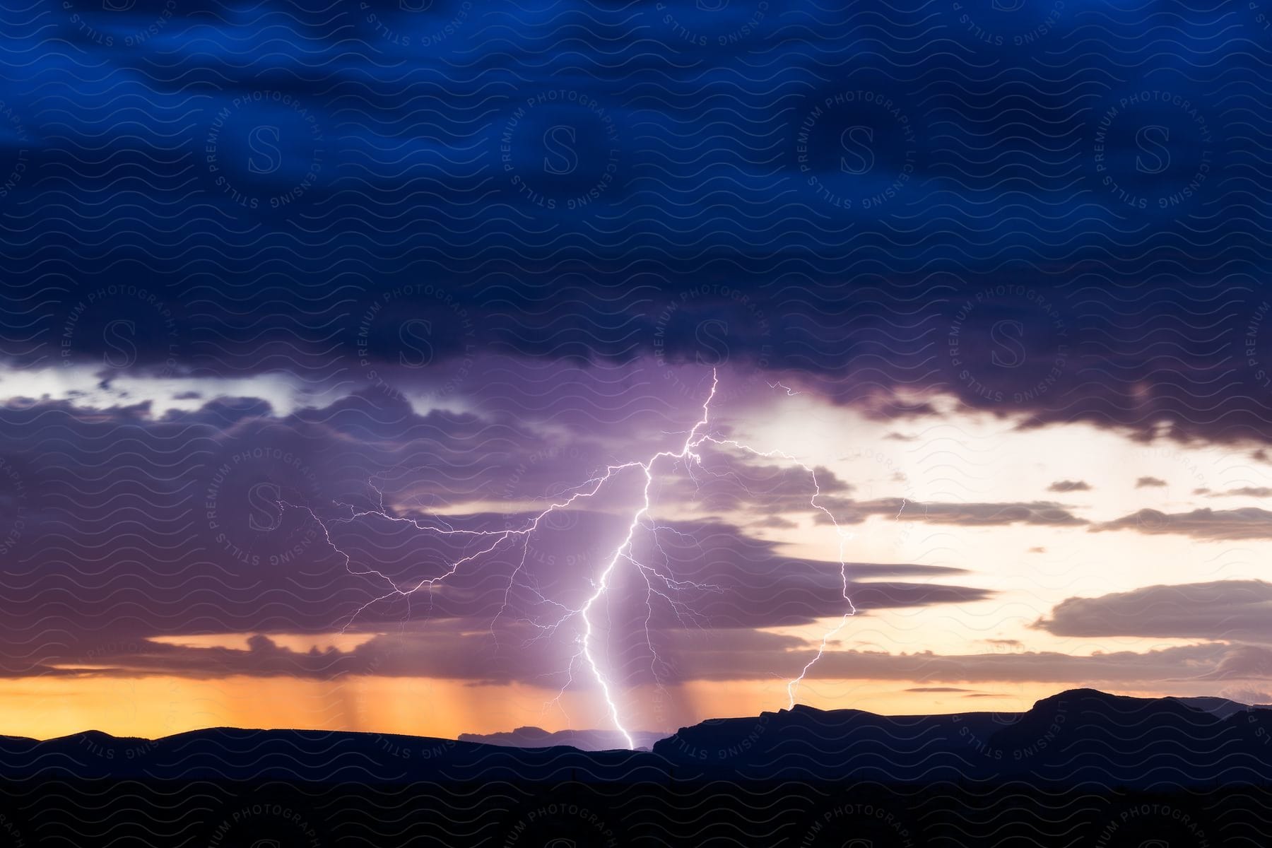 A lightning bolt strikes down from dark clouds as the sun sets in the background