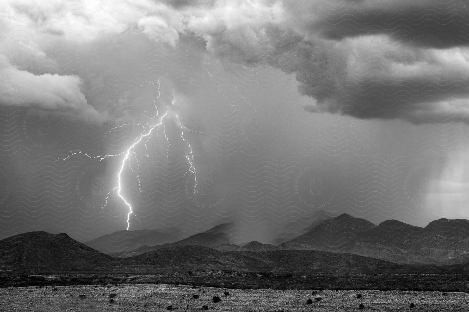 A bolt strikes in the mountains during a thunderstorm in a rural area