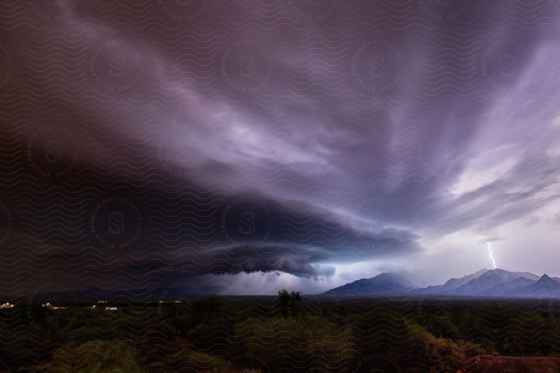 A powerful thunderstorm over grasslands and mountains during dusk