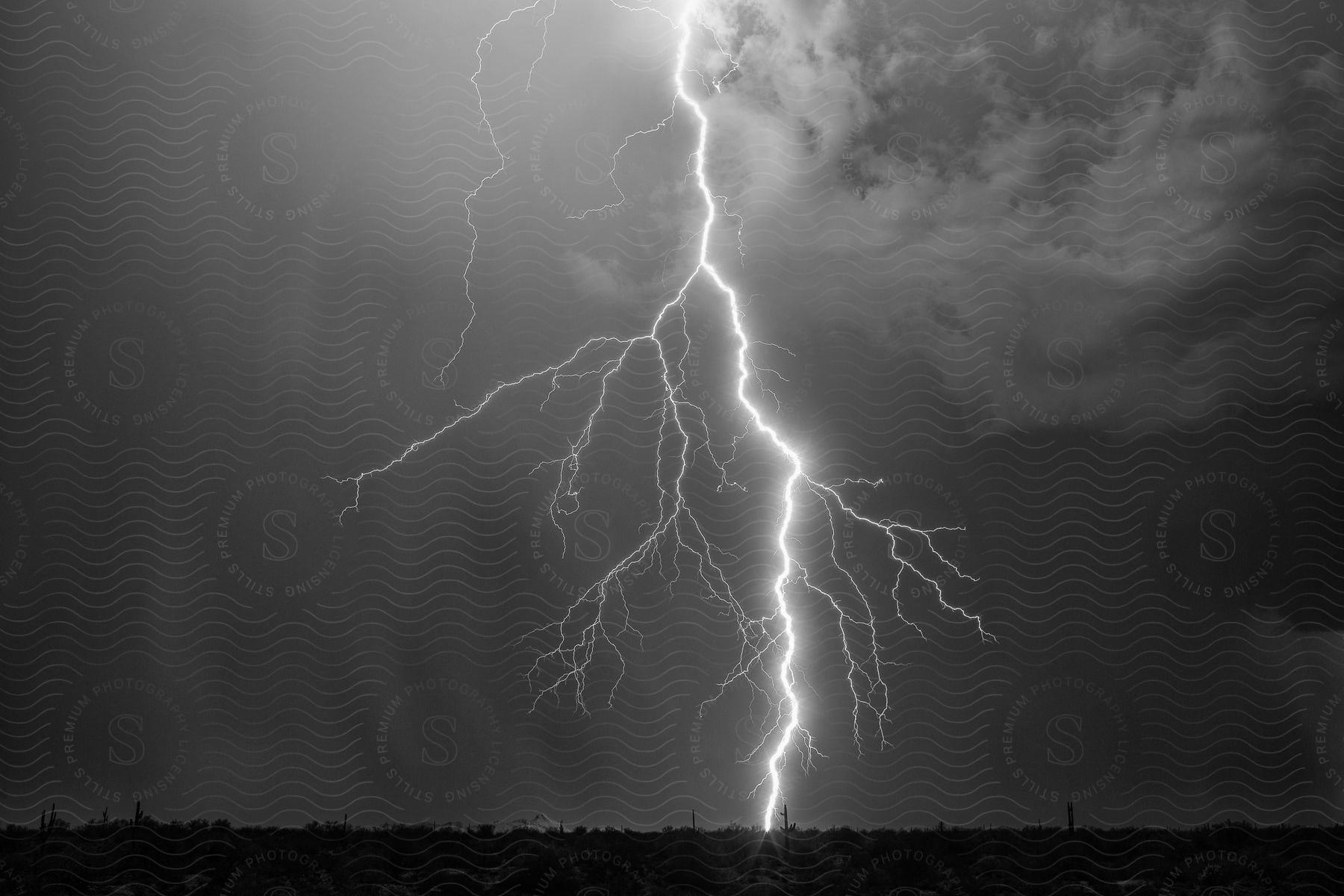 A lightning bolt strikes rural land at the end of an open road emerging from a storm cloud