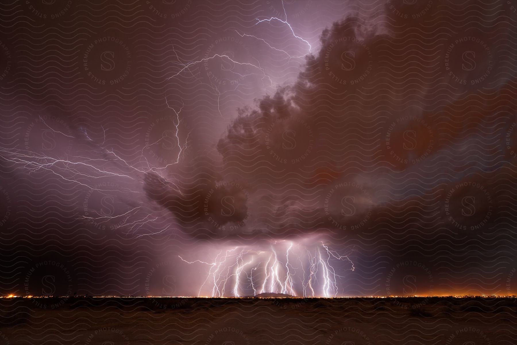 Lightning strikes hit the ground multiple times around a city at night