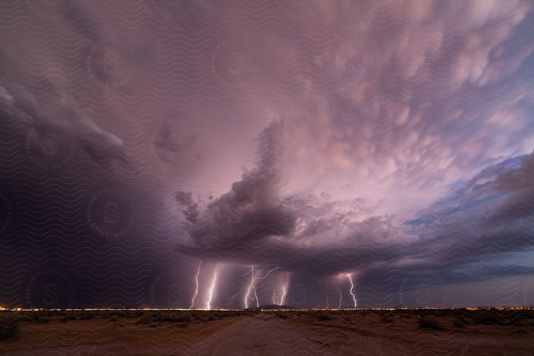 A stormy dusk sky with lightning strikes illuminating the horizon