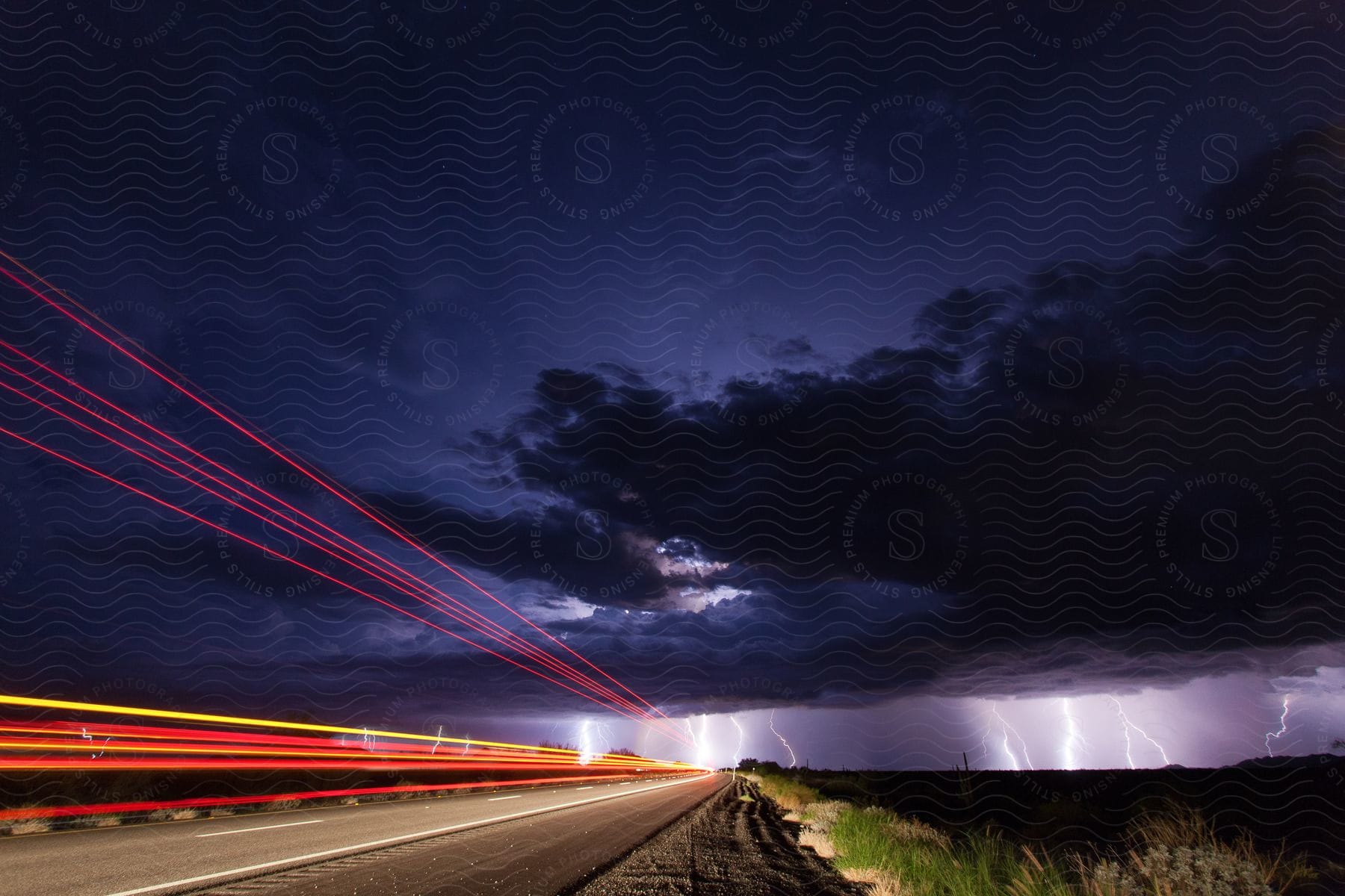 Cars drive down the highway toward a thunderstorm