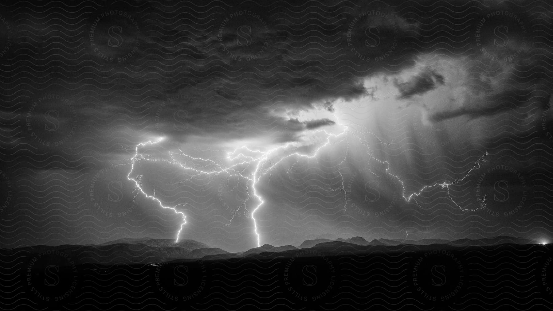 Lightning illuminates storm clouds over mountains in bisbee az