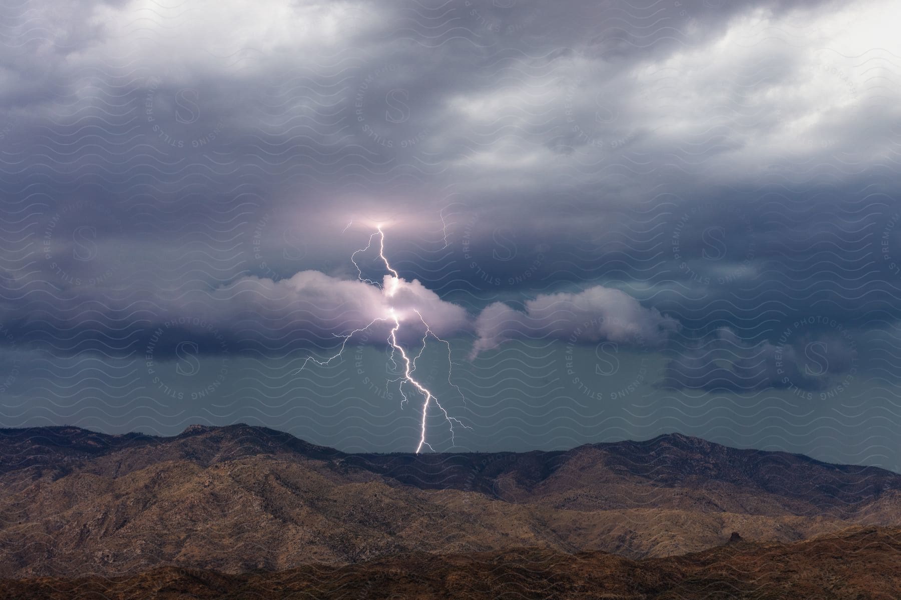 Bolts of lightning flash over barren mountains in this landscape