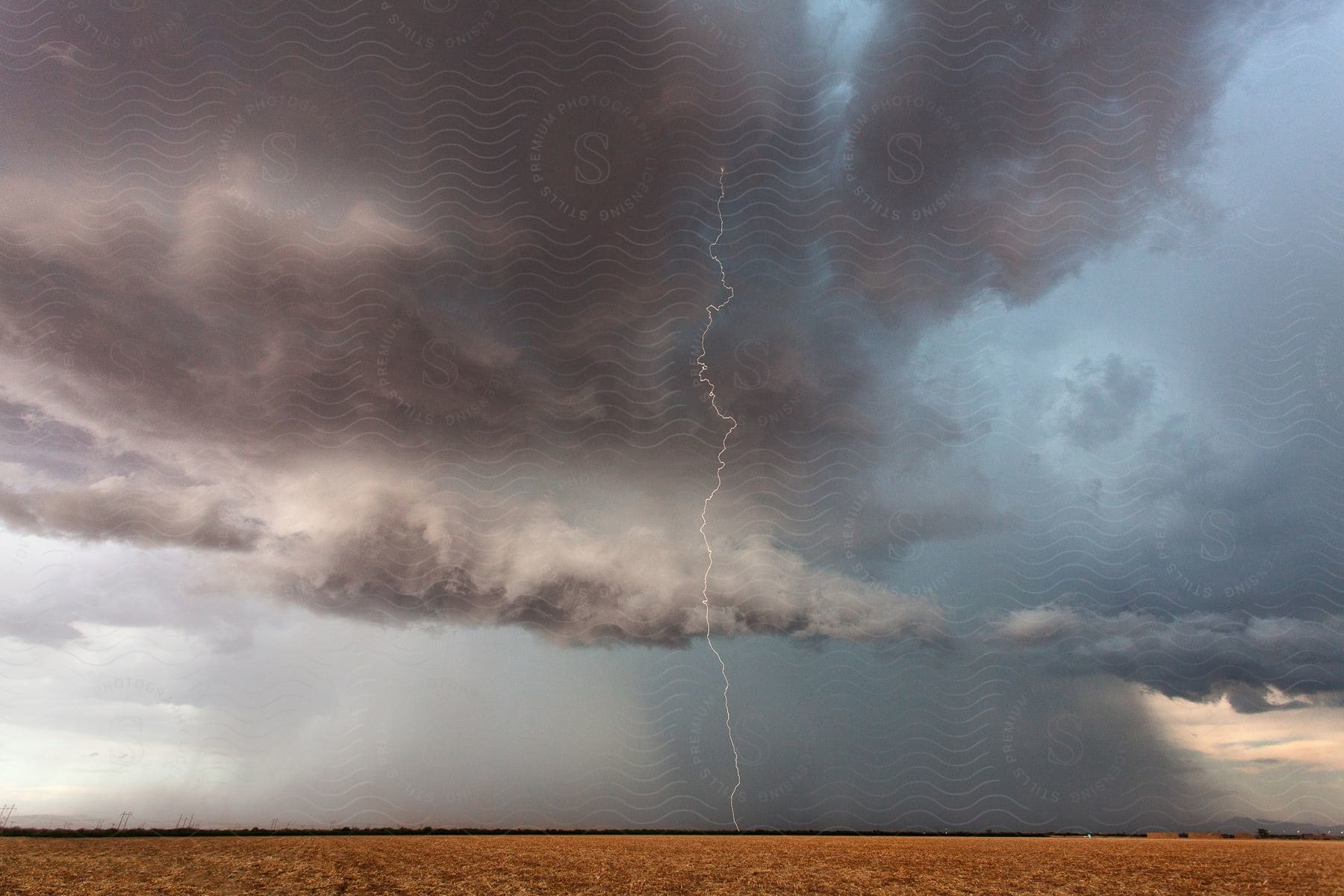 Lightning strike on a field in the midwest under the rain during the daytime