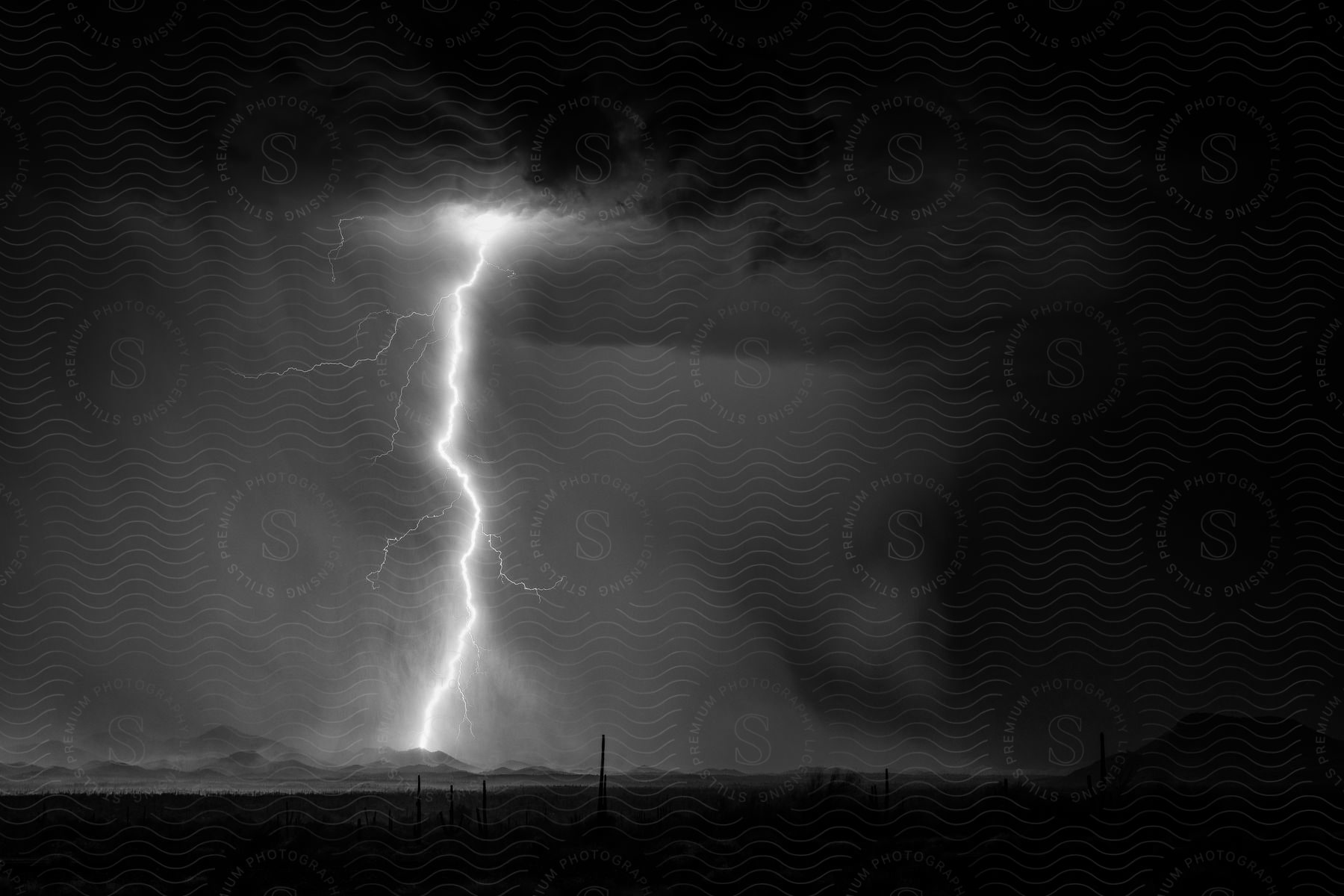 A lightning bolt strikes near mountains in a stormy sky