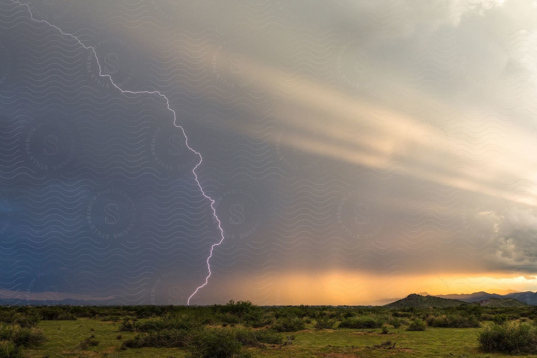 Vibrant thunder strike illuminates the evening sky creating a dramatic scene with colorful hues while lush green grasses cover the field