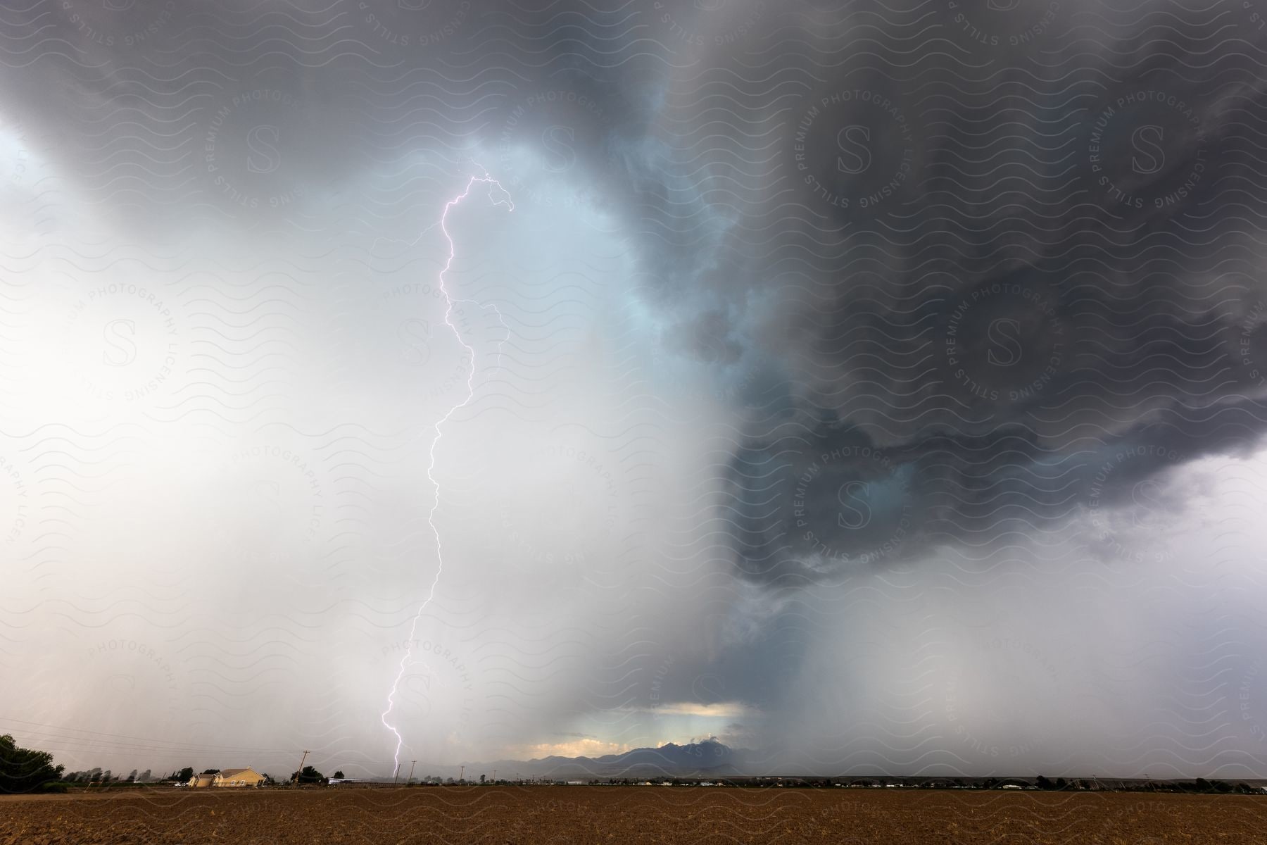 Lightning and rain falling from storm clouds over the mountains in the plains