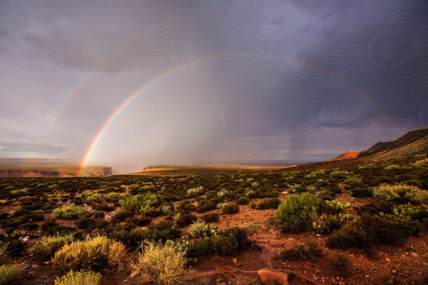 A rainbow extending over a desert landscape after a storm