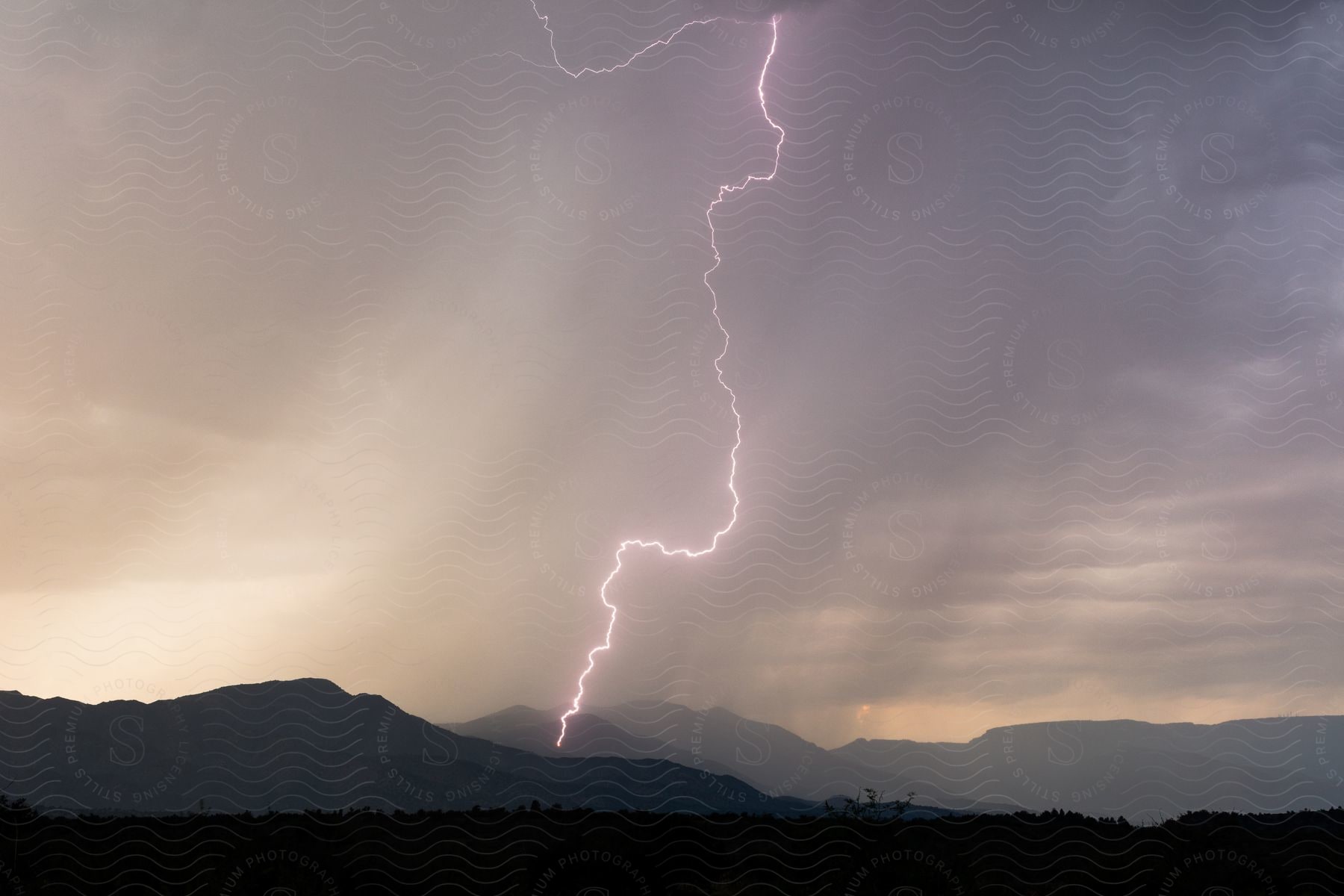 Lightning strikes down on a valley in the outdoors at night time