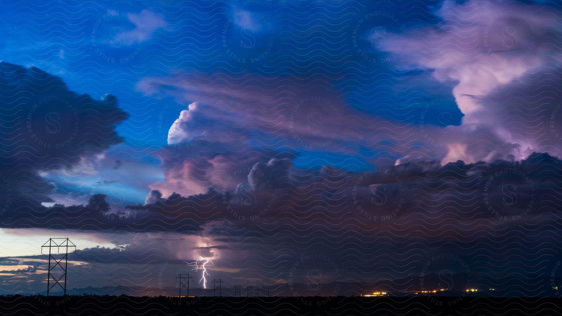 Lightning strikes the ground near a town in the countryside at evening