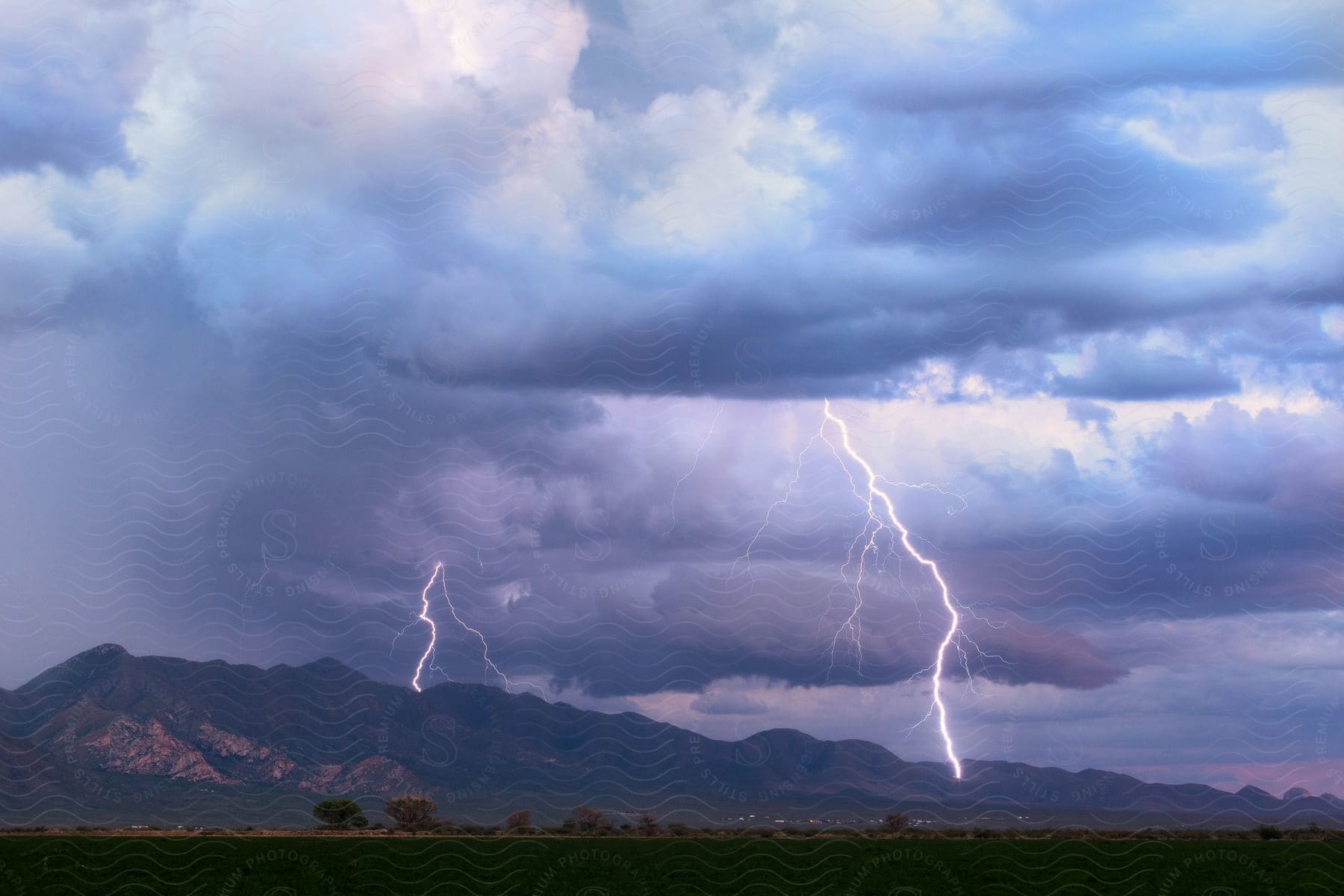 A clear air bolt strikes the chiricahua mountains in arizona during a thunderstorm at dusk creating a contrast between blue and lilac colored sky and clouds