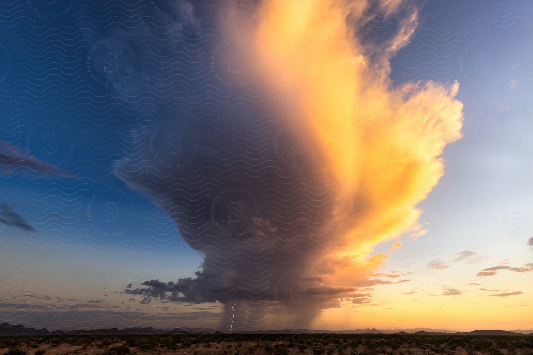 Supercell storm with lightning strikes over desert mountains on horizon
