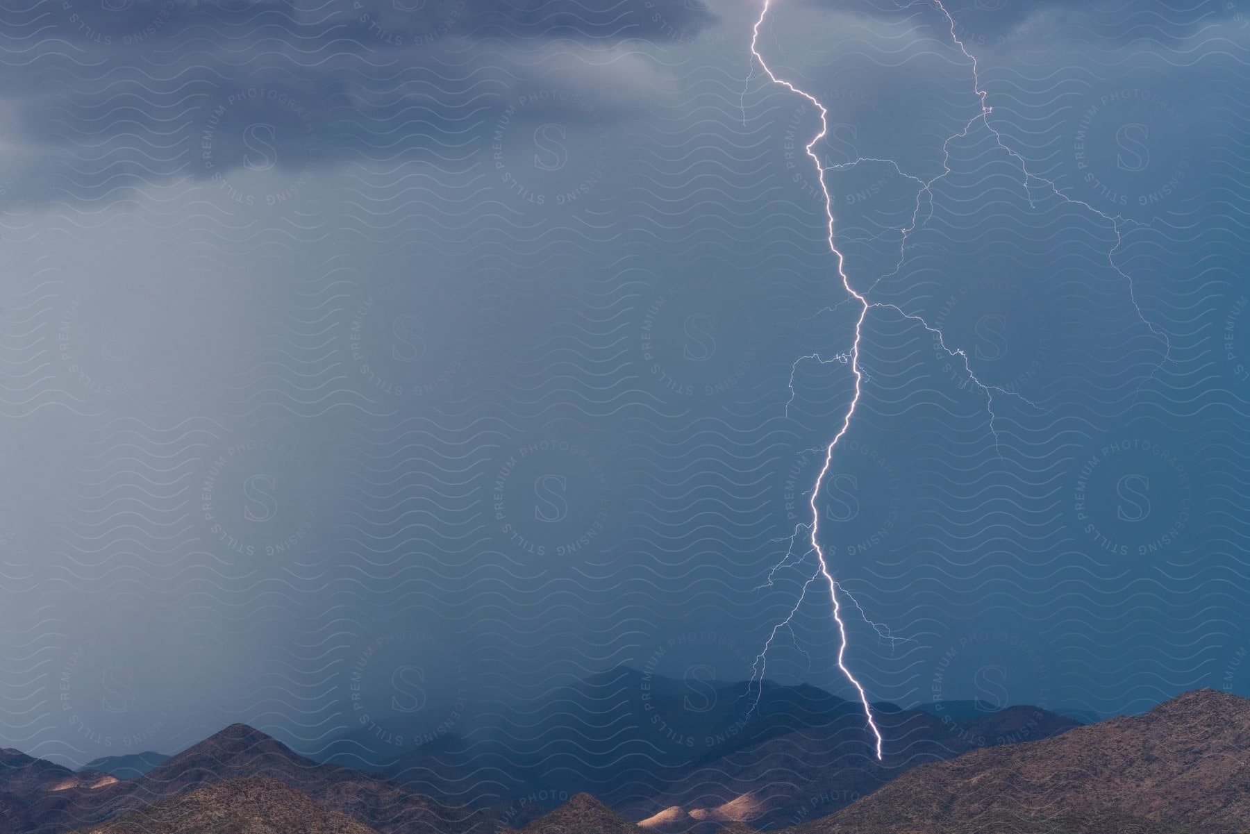 Lightning strikes a mountain range in arizona during a thunderstorm