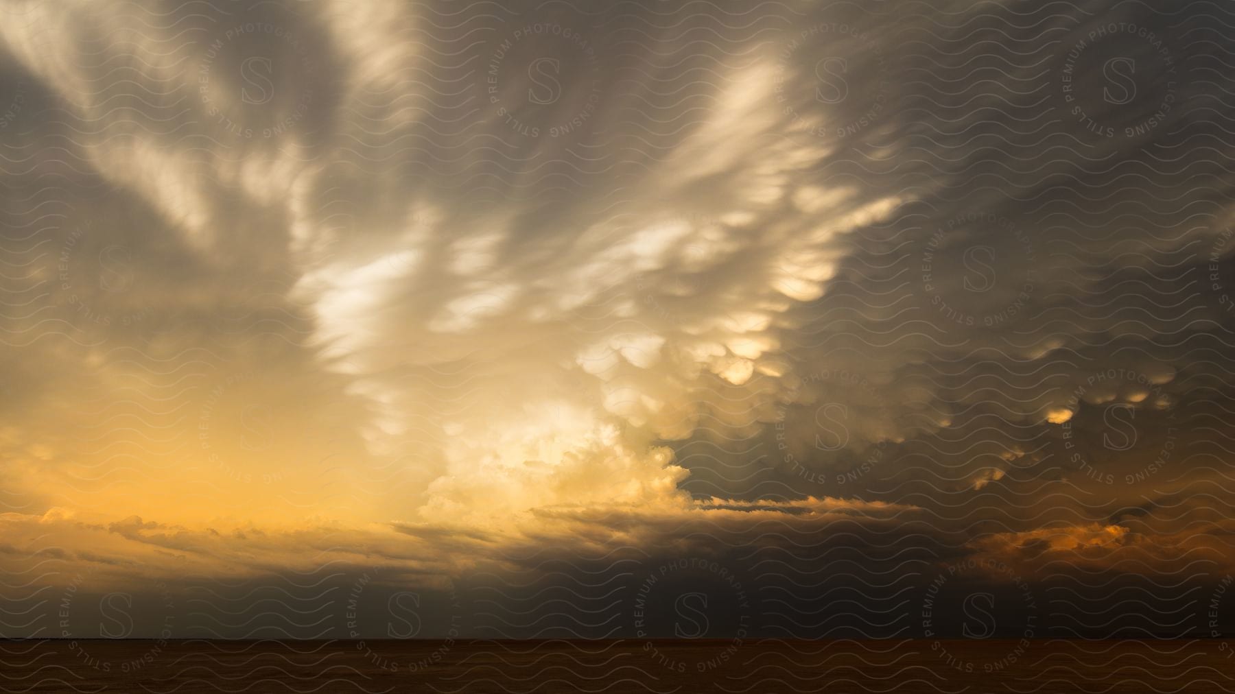 Sunset over grassland on a cloudy day near willcox arizona with stunning mammatus clouds and thunderstorms seen from the dry lake bed