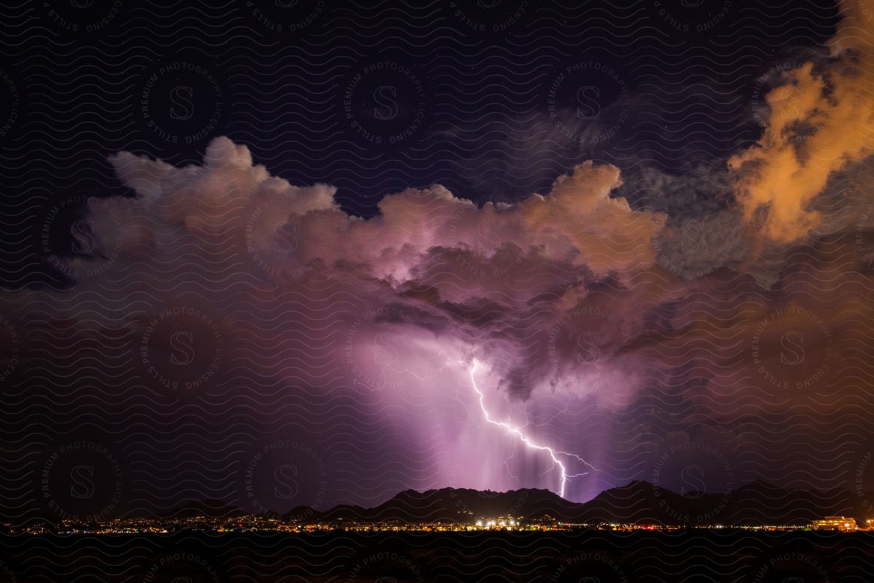 Mountains illuminated by a lightning bolt under storm clouds at night