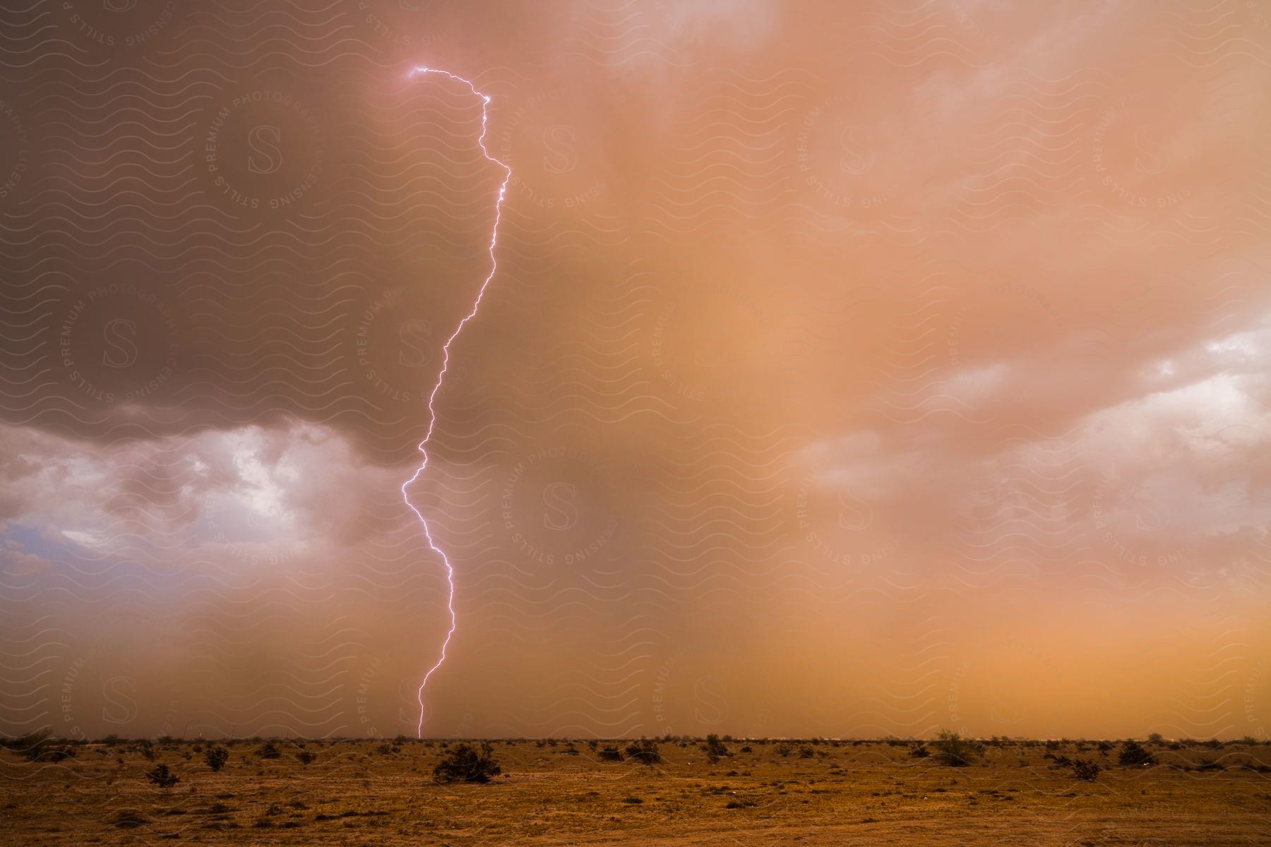 Flat landscape with thunder cutting through the cloudy sky during a storm in the arizona desert
