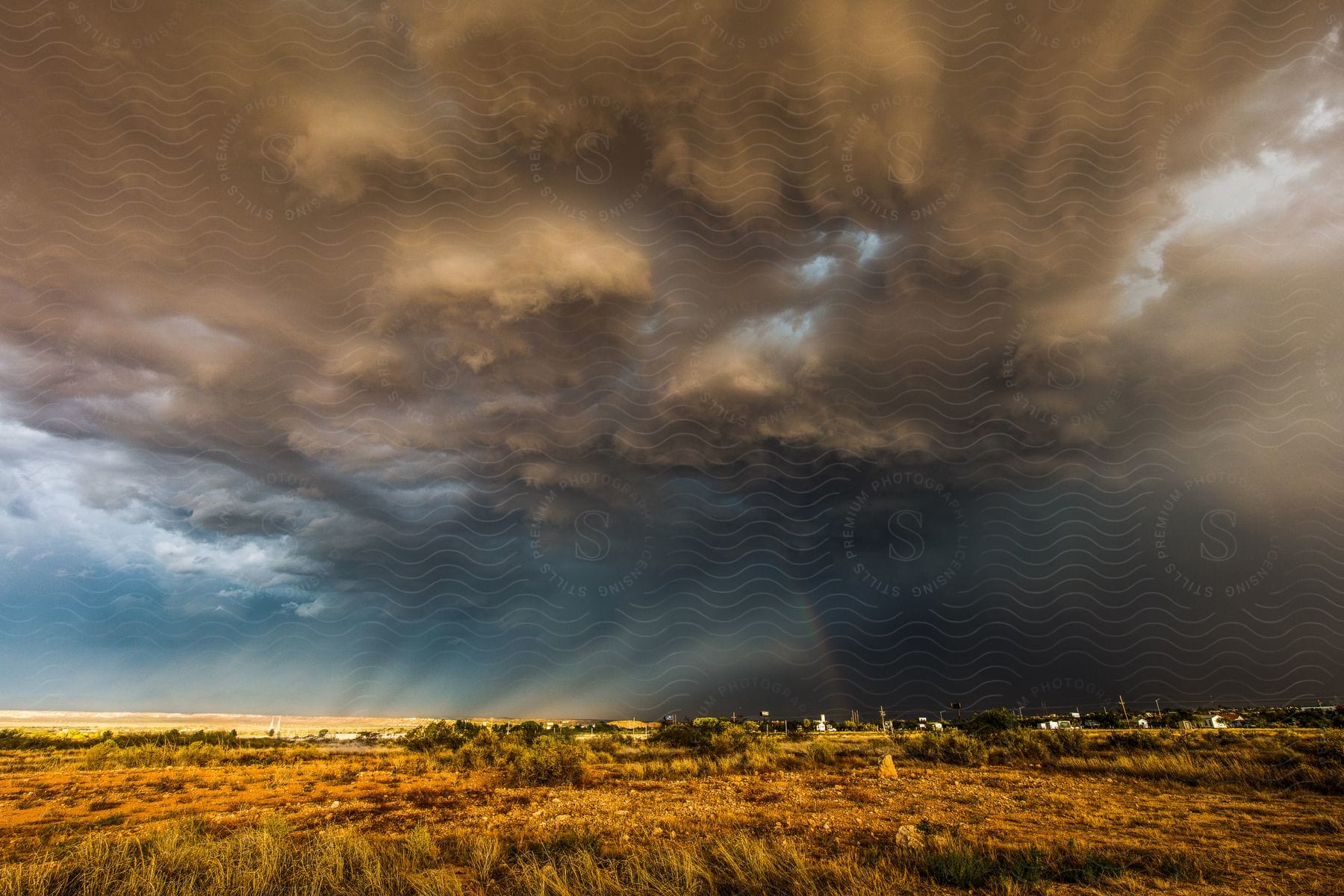 A storm hovers over benson arizona with a partial rainbow and rays of light shining through